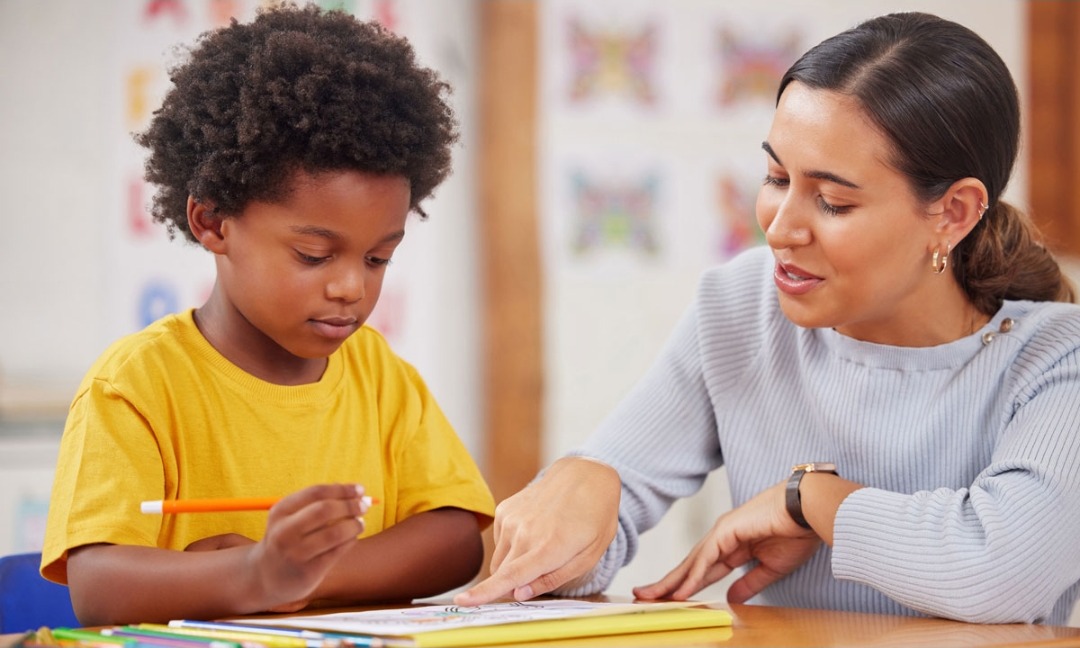 A tutor working one-on-one with a young student on a reading exercise