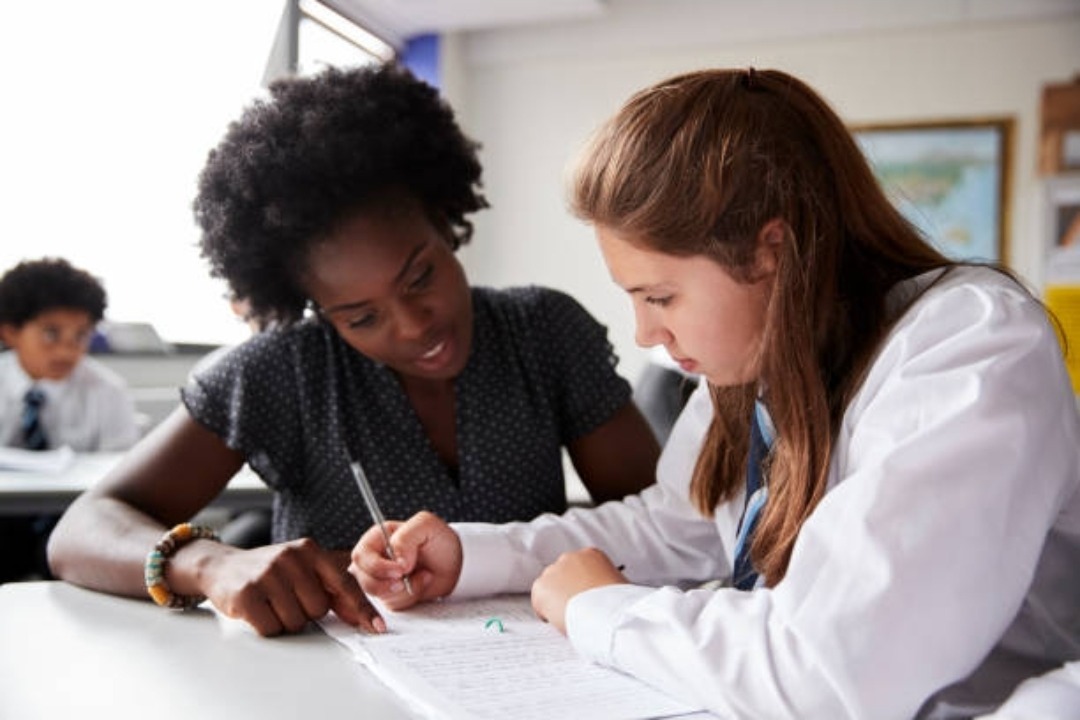 A tutor working one-on-one with a student on a writing exercise in a classroom
